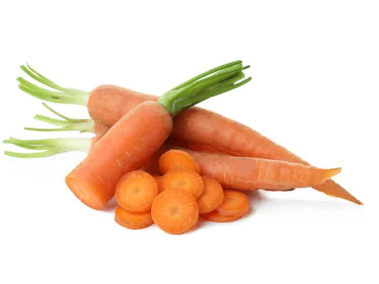 Stack of ripe carrots with cut tops isolated on white background