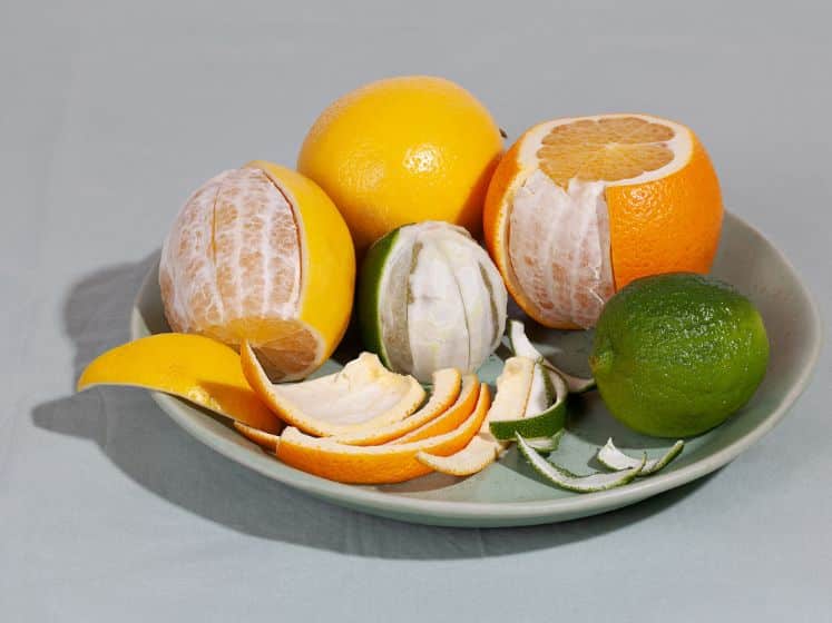 Fruit citrus with peels on green plate. Concept reducing food waste