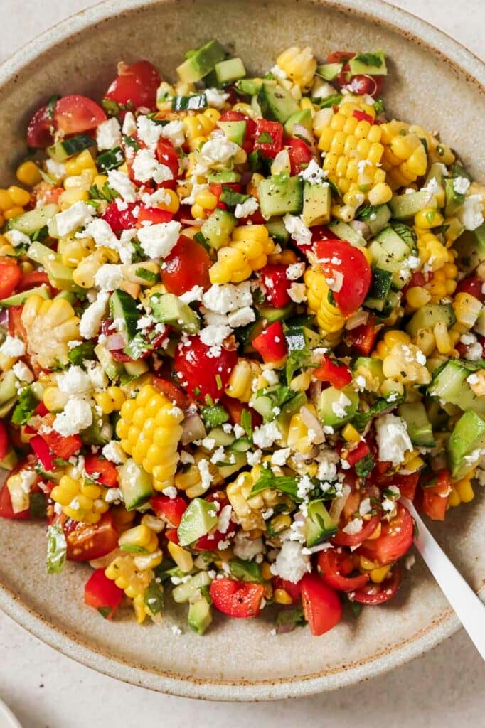 Fresh corn salad on a plate with a spoon.