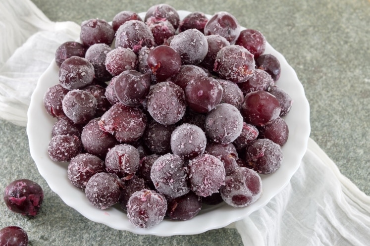 Frozen grapes in a white bowl.