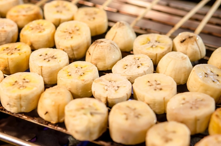 Banana slices on skewers on a grill.