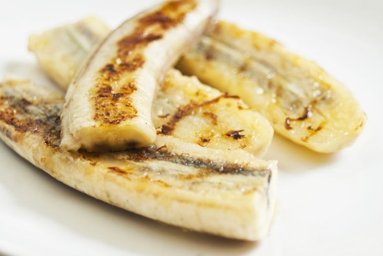 Grilled bananas on a white plate.
