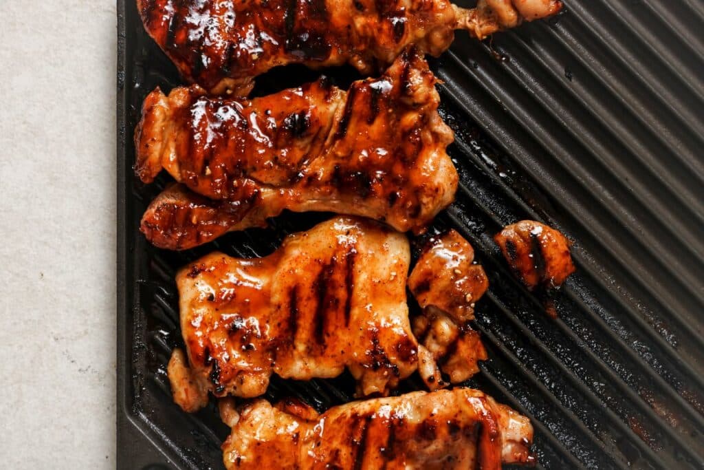Hot honey chicken thighs on a grill.