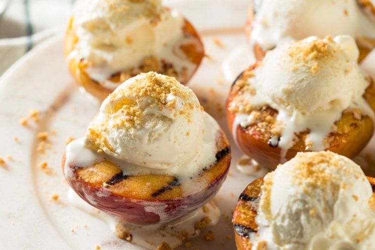 Grilled peaches topped with a scoop of ice cream.