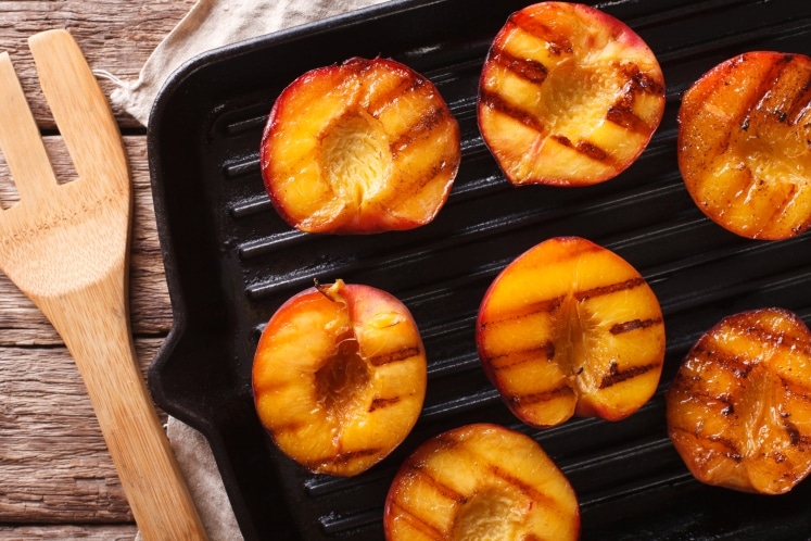 Peaches with grill marks on a grill.