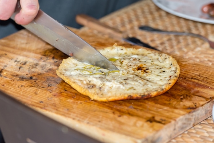 Grilled provolone cheese being sliced with a knife.
