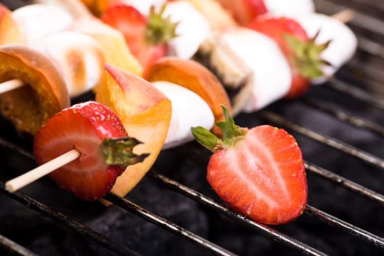 Skewered strawberries on a grill.