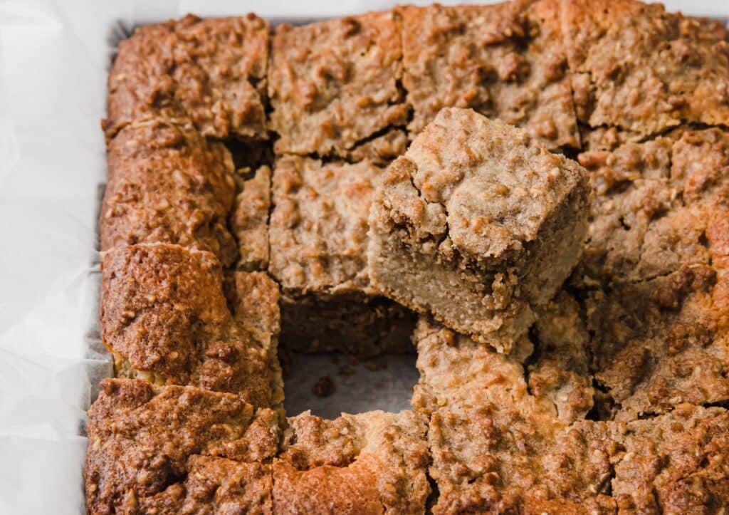 A baked coffee cake dish with a square piece missing and placed on top of the remaining portion.