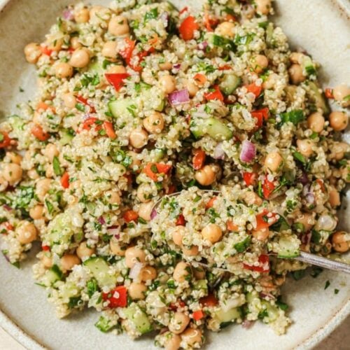 Quinoa chickpea salad being scooped with a spoon on a plate.