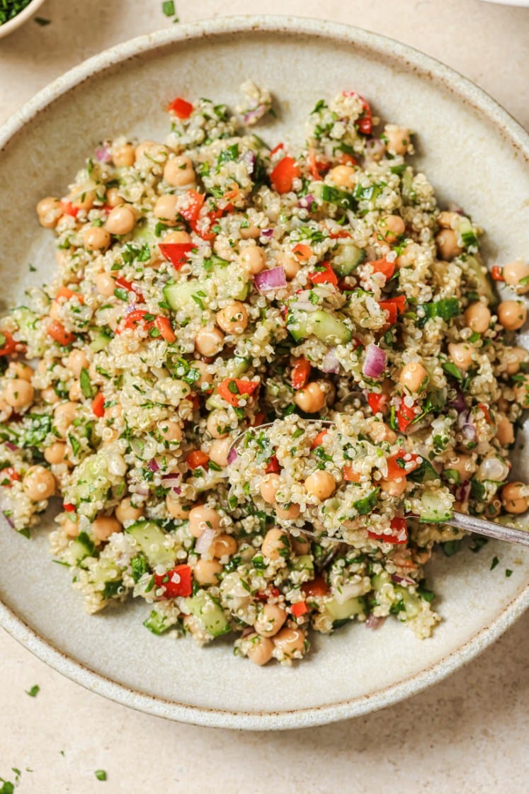 Quinoa chickpea salad being scooped with a spoon on a plate.