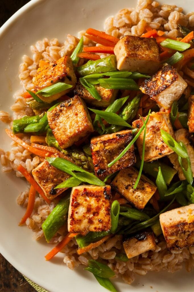 Tofu stir fry with brown rice on a plate.