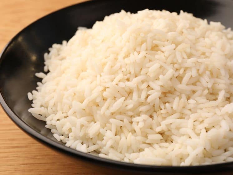 Plate with delicious rice on wooden table, closeup