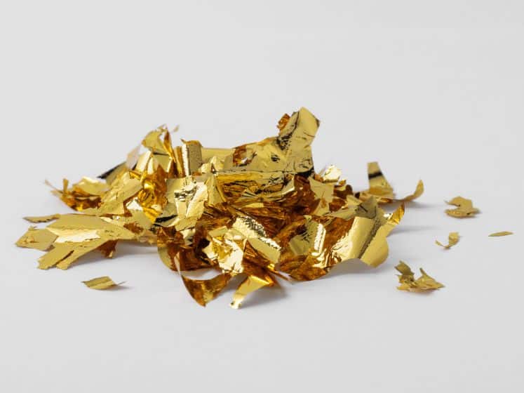 Pile of edible gold leaf on white background