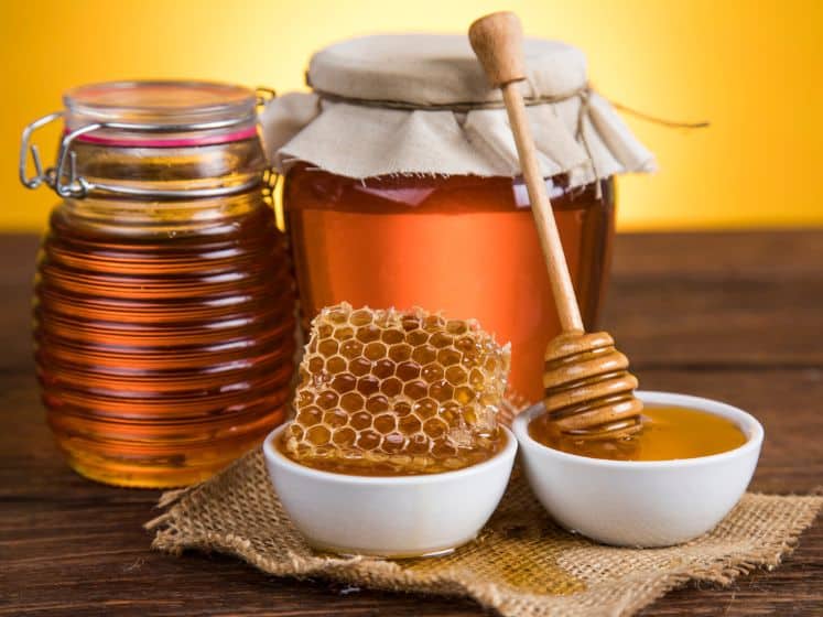 Honey and honey comb on a wooden table.