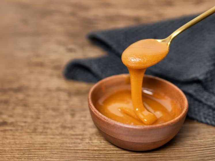 Manuka honey dipper dipping in raw organic liquid