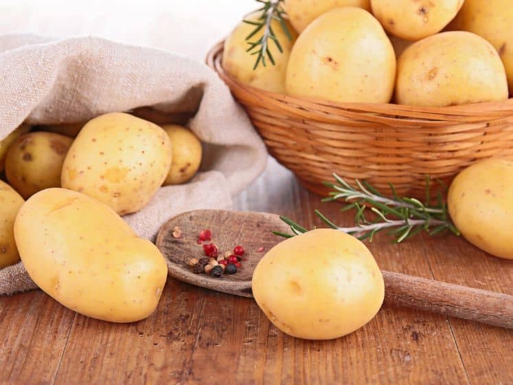 Potatoes on a counter, in a bag, and in a basket.