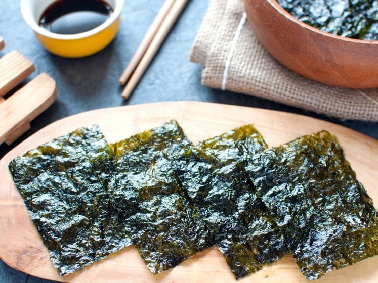 Dried seaweed wafer snacks on a wooden board closeup with dishware