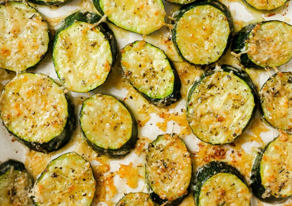 Baked sliced zucchini on top of parchment paper.