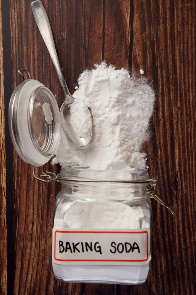 Baking soda in a jar spilled over the table with a spoon over it.