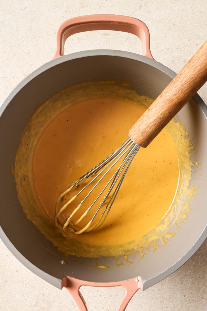 Cheese dip in a pot with a whisk.