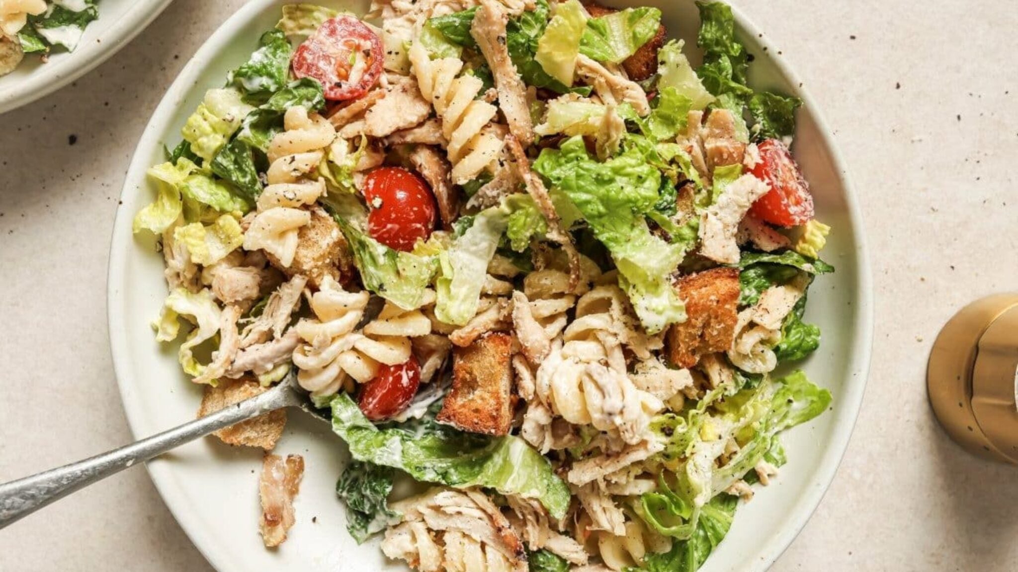 Chicken caesar pasta salad with romaine, croutons, chicken, and parmesan in a bowl.