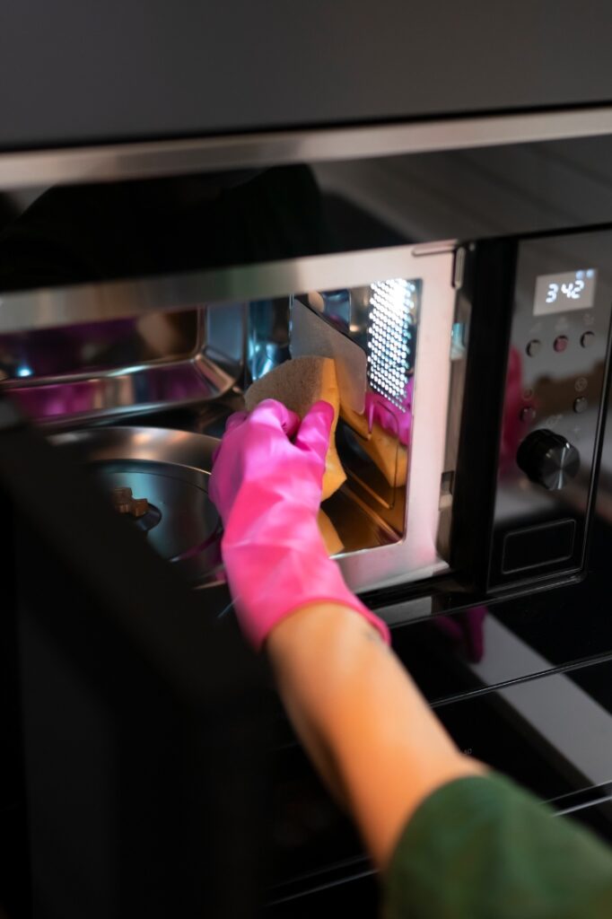 A person cleaning the inside of a microwave.