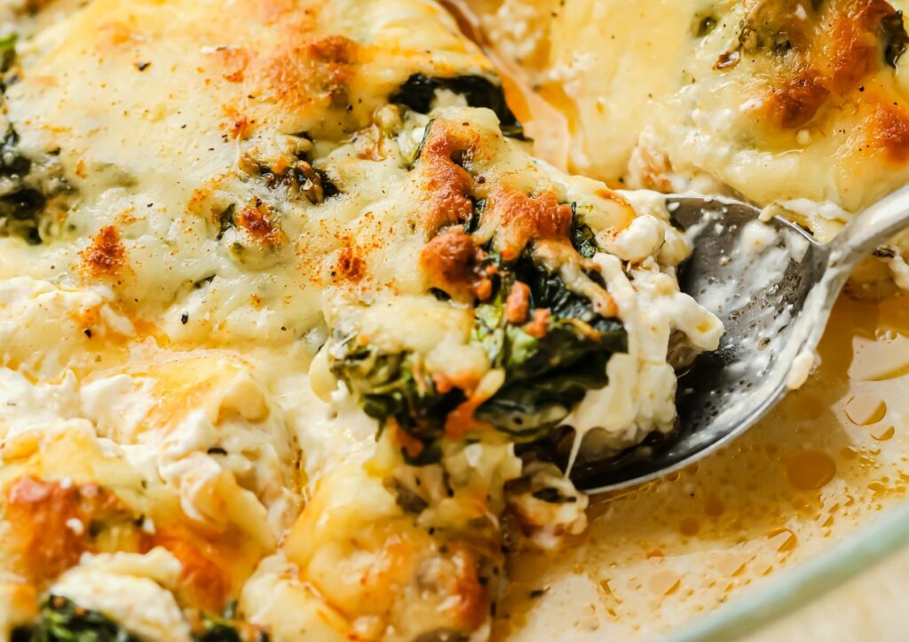 A spoon serving spinach chicken bake.