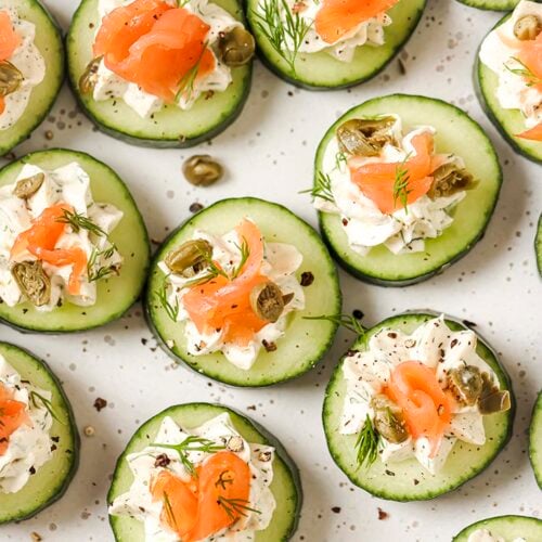 Garnished cucumber and dill smoked salmon appetizer on a plate.