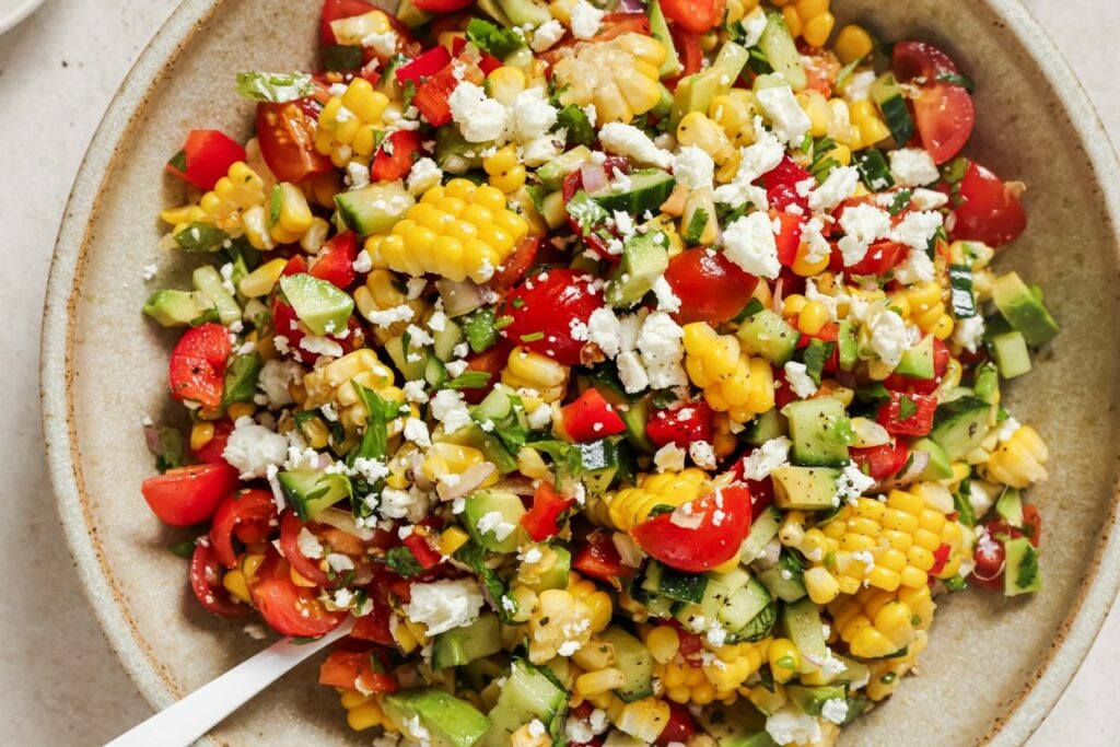 Fresh corn salad garnish with feta crumbles and fresh herbs.