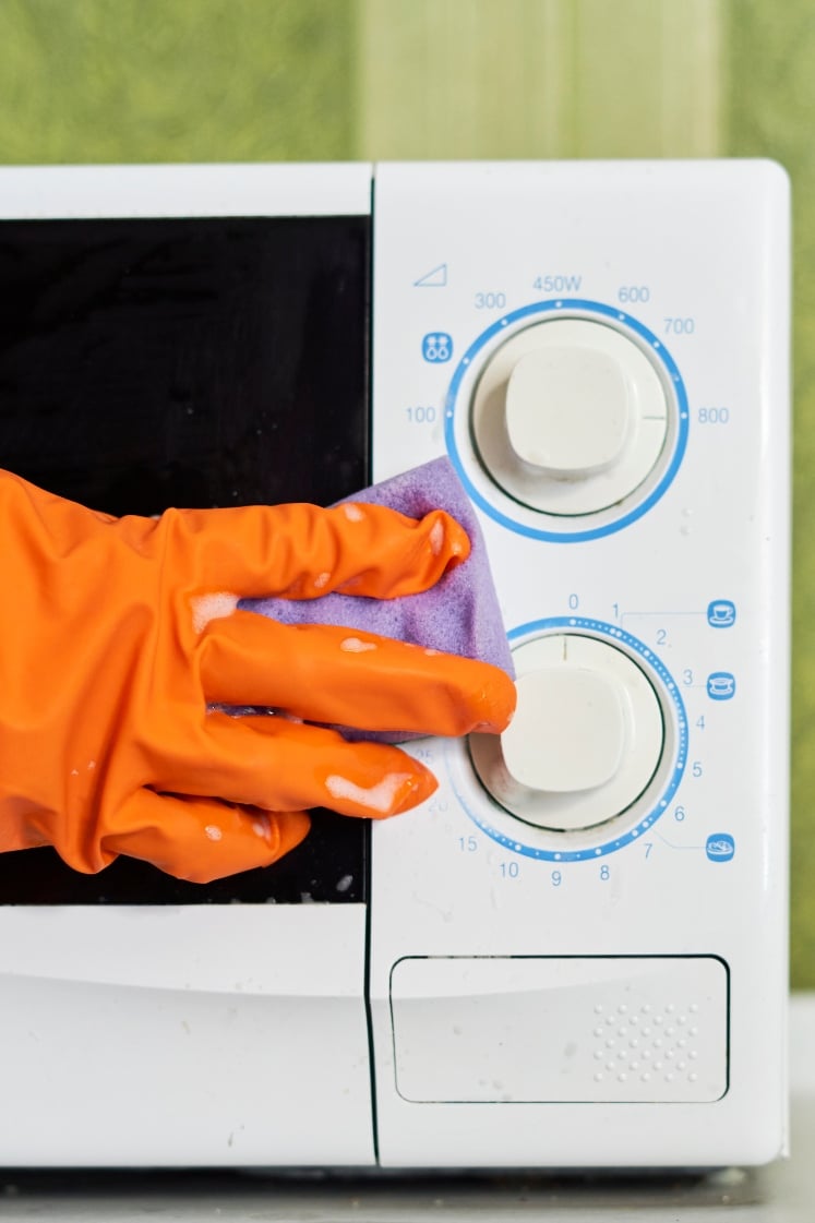 A person cleaning a microwave.