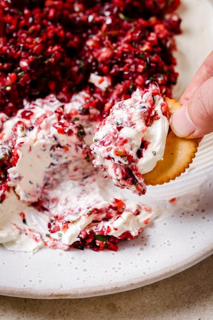 A cracker dipped into jalapeño cranberry dip.