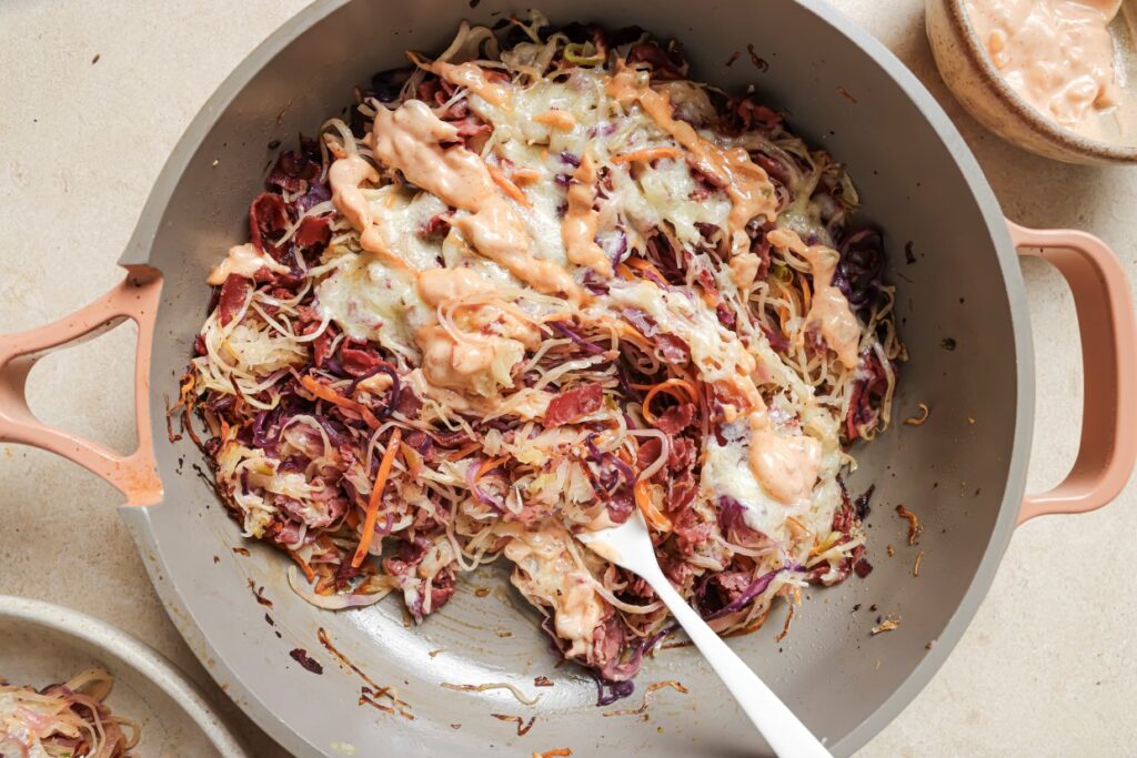 Reuben bowls in a skillet with a fork.