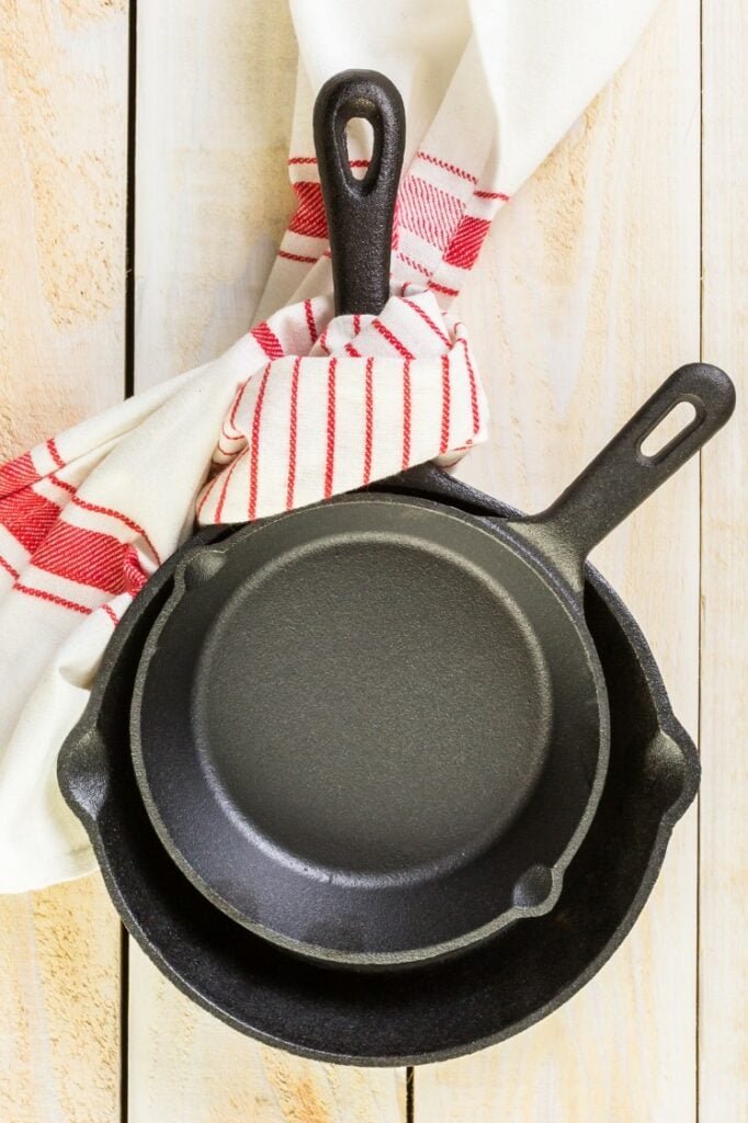 Stacked cast iron skillets with a dish towel.