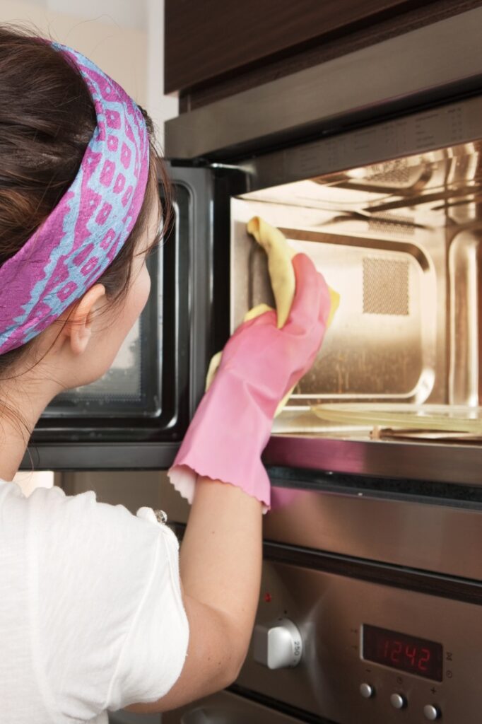 A person cleaning the inside of a microwave.