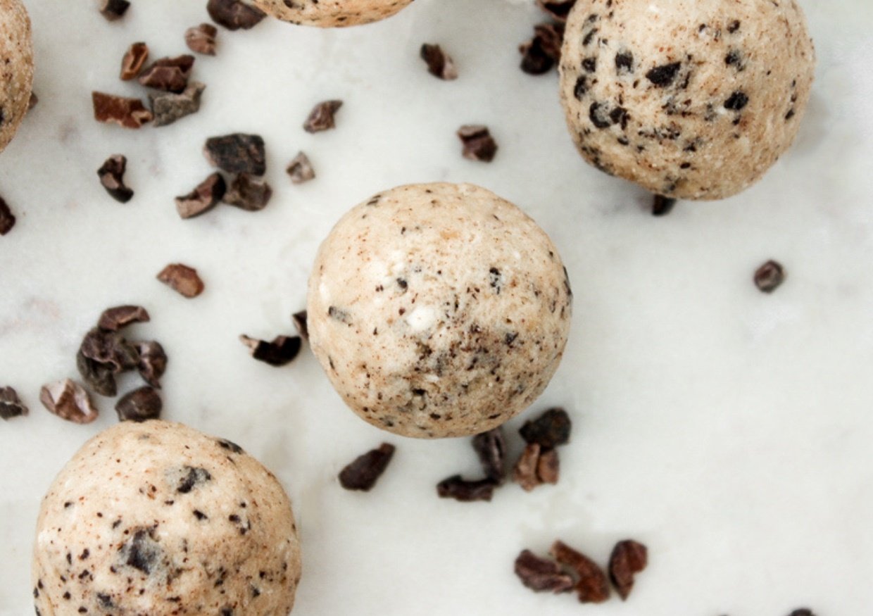 Chocolate chip cookie dough fat bombs on a marble countertop.