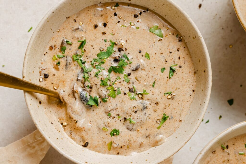 A bowl of Hungarian mushroom soup garnished with fresh herbs.