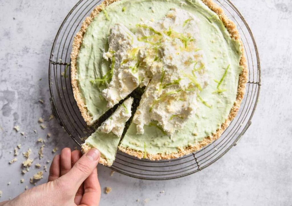 A hand grabbing a slice of keto key lime pie.