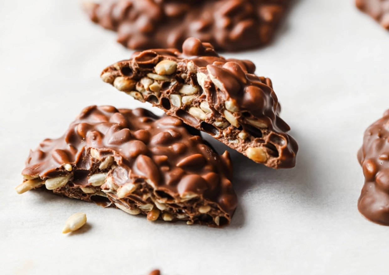 Two halved low-carb milk chocolate sunflower seed clusters.