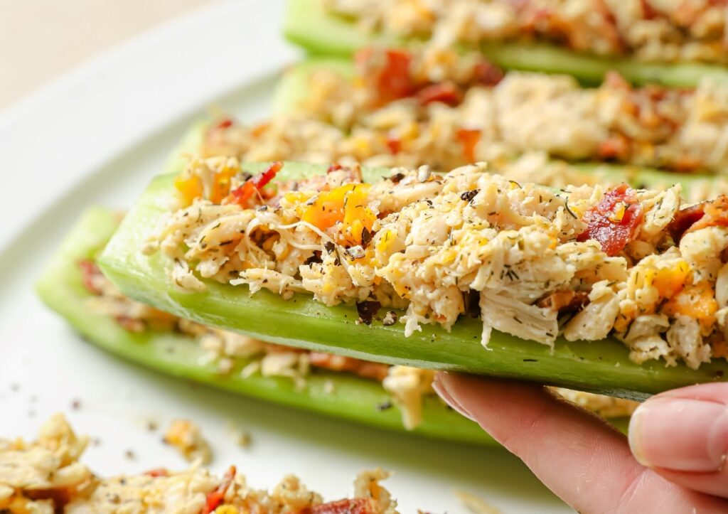 A hand holding a bacon ranch chicken salad cucumber boat.