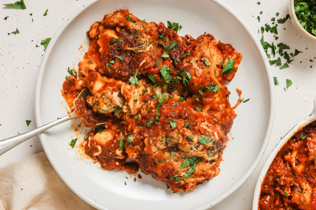 A plate of baked ravioli topped with fresh herbs.