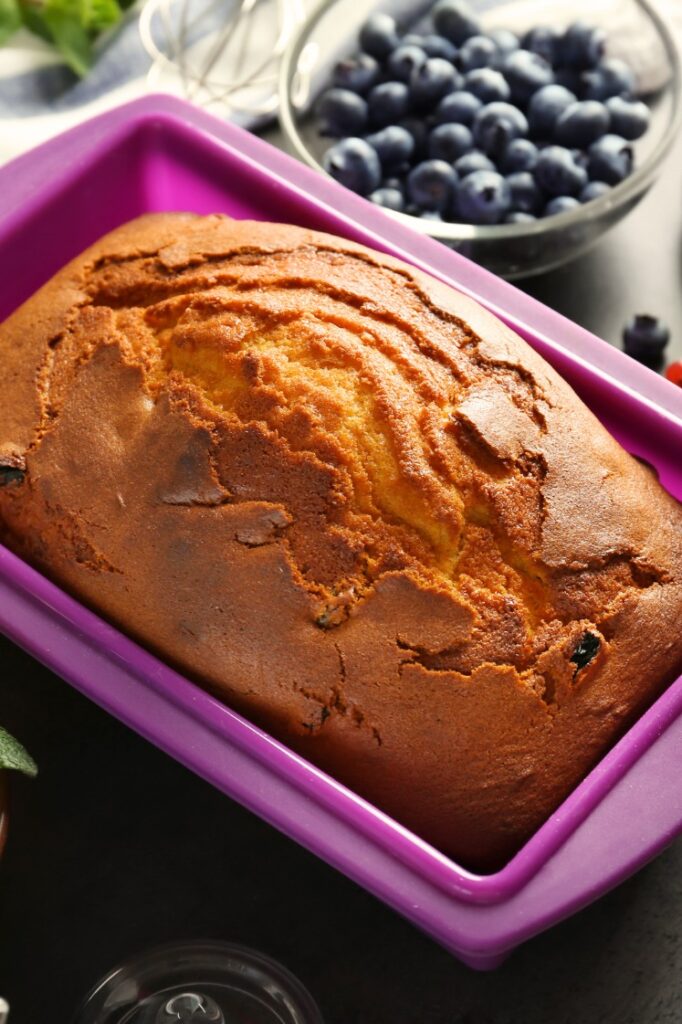 Freshly baked loaf of banana bread on a purple silicone baking mold.