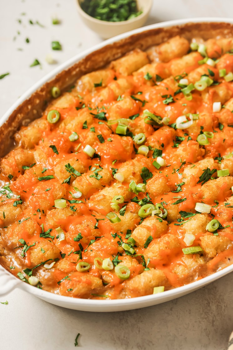 Chicken tater tot casserole in a baking dish garnished with green onions.