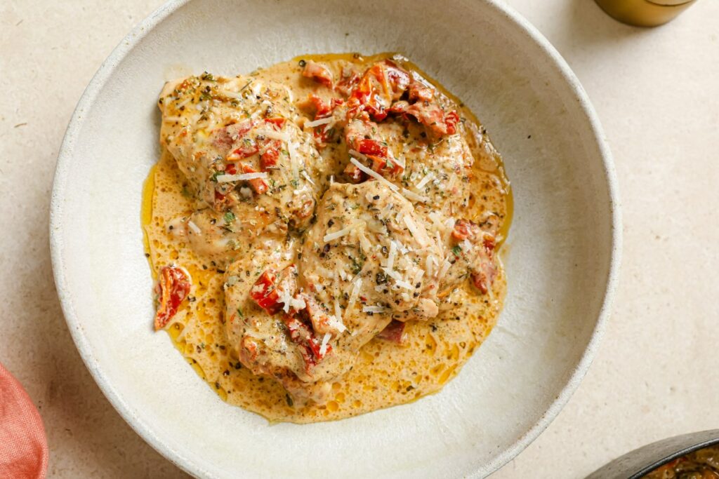 Creamy sun dried tomato chicken on a plate garnished with Parmesan.