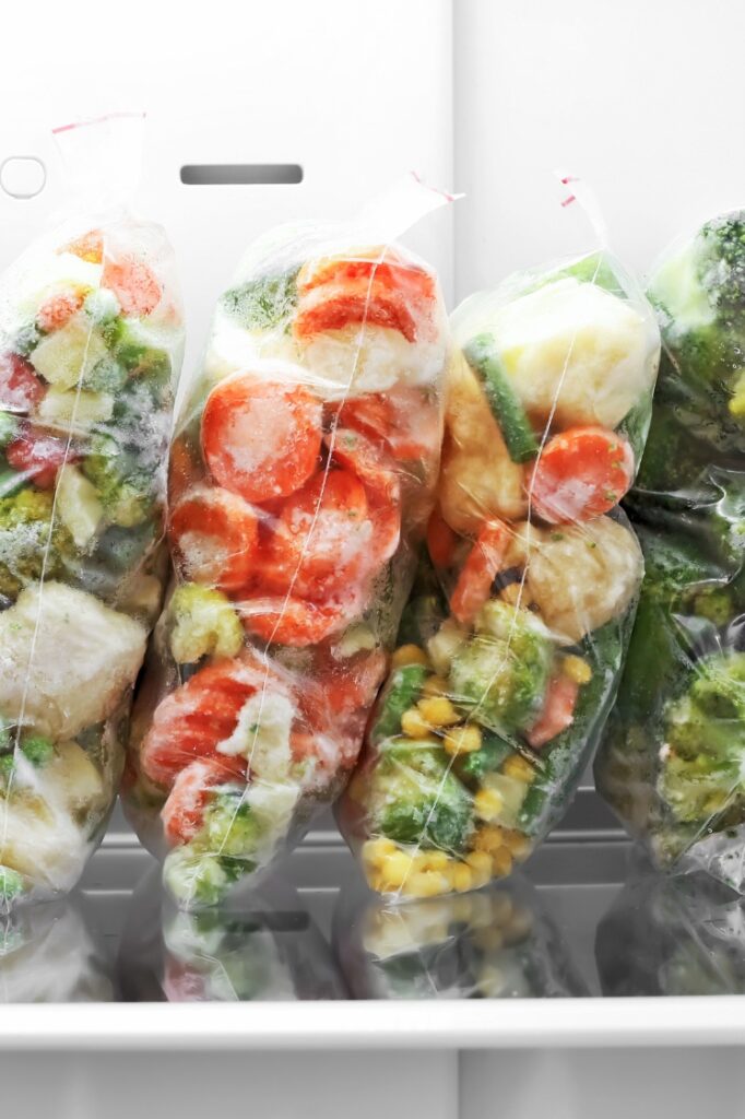 Plastic storage bags with frozen vegetables in the fridge.