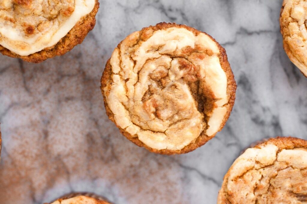 Low-carb cream cheese pumpkin muffins on a marble countertop.