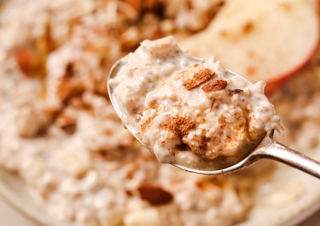 A spoonful of creamy oatmeal with chunks of nuts and sprinkled with cinnamon.