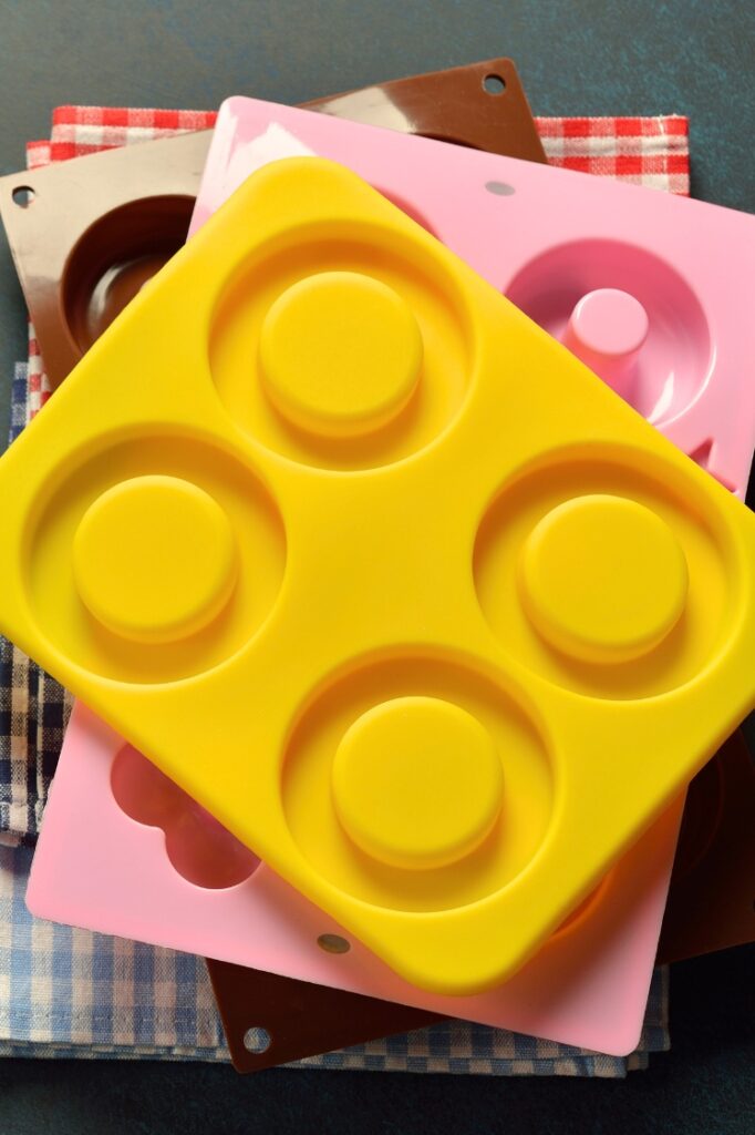 A stack of silicone baking molds on top of folded, checkered cloths.