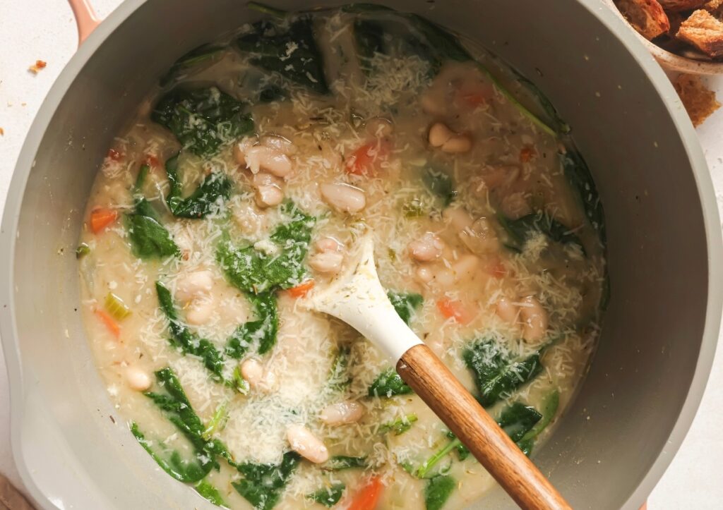 White bean soup in a pot with a spoon.