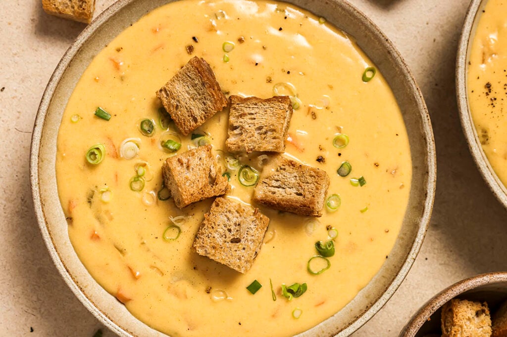 A bowl of Wisconsin beer cheese soup with croutons and chives.