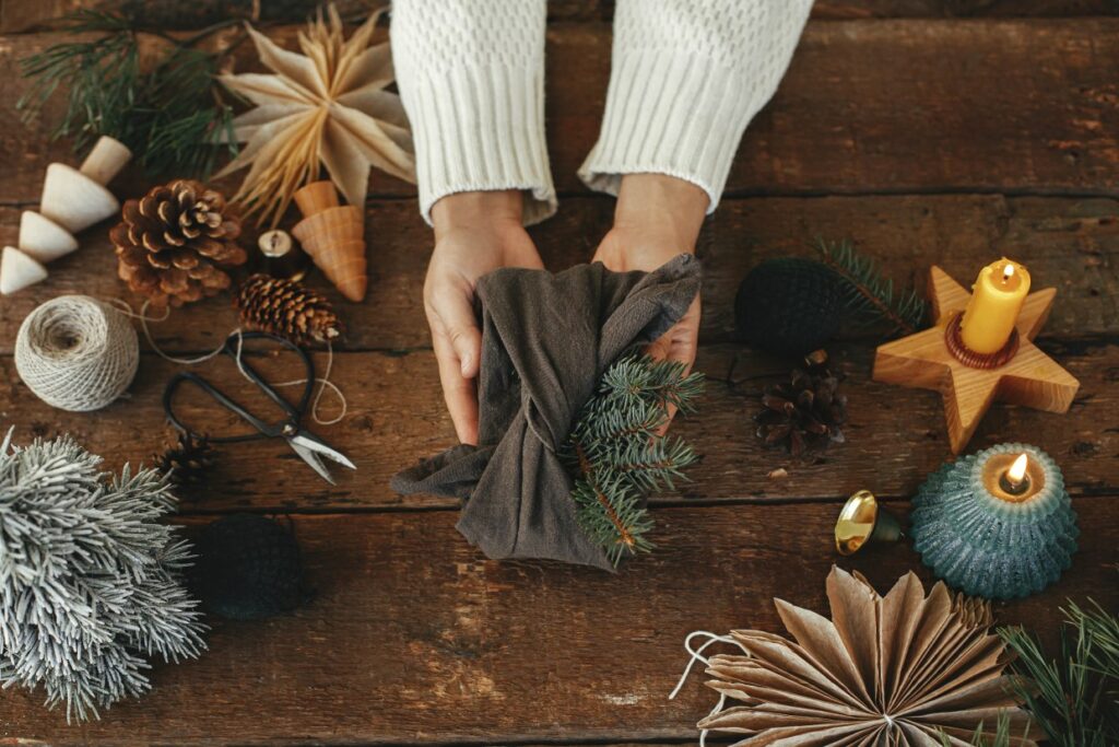 A person holding a cloth with pieces of a pine tree along with other holiday crafting items.